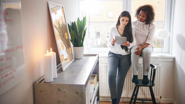 Zwei Frauen auf der Fensterbank mit Laptop