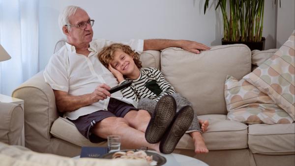 Alter Mann mit jungen Menschen beim Fernsehen