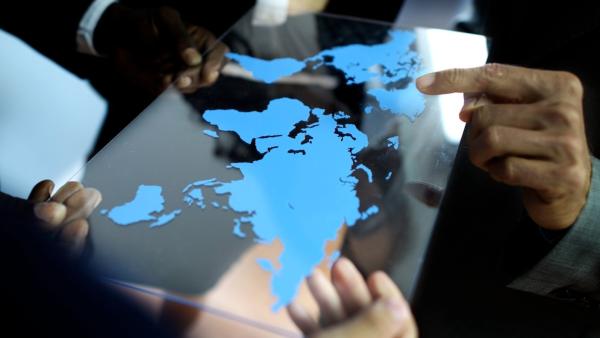 Viele Finger zeigen auf eine Weltkarte