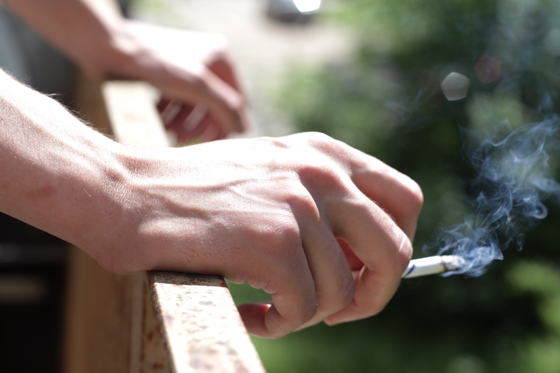 Eine Hand hält eine rauchende Zigarette