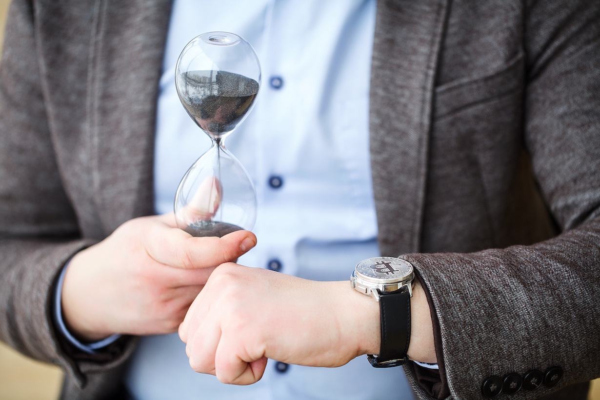 Mann mit Uhr und Sanduhr in der Hand