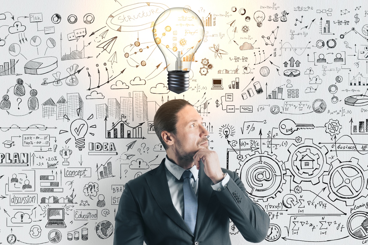 Nachdenklicher junger Geschäftsmann mit glühender Glühbirne und Geschäftsskizze auf Betonwand