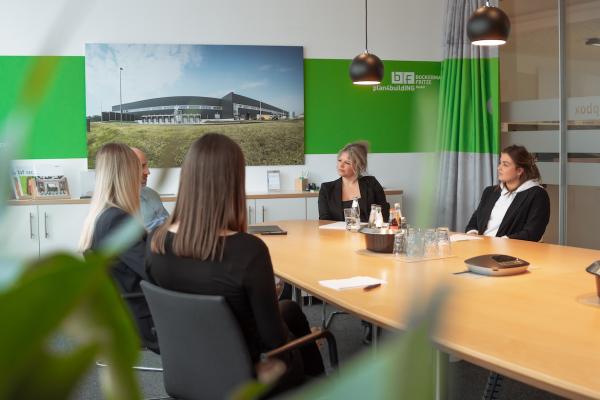 Fünf BüromitarbeiterInnen an einem Tisch in Besprechung