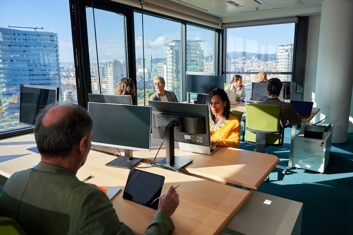 Geschäftsteam arbeitet an Computern in einem modernen Büro mit Blick auf die Stadt