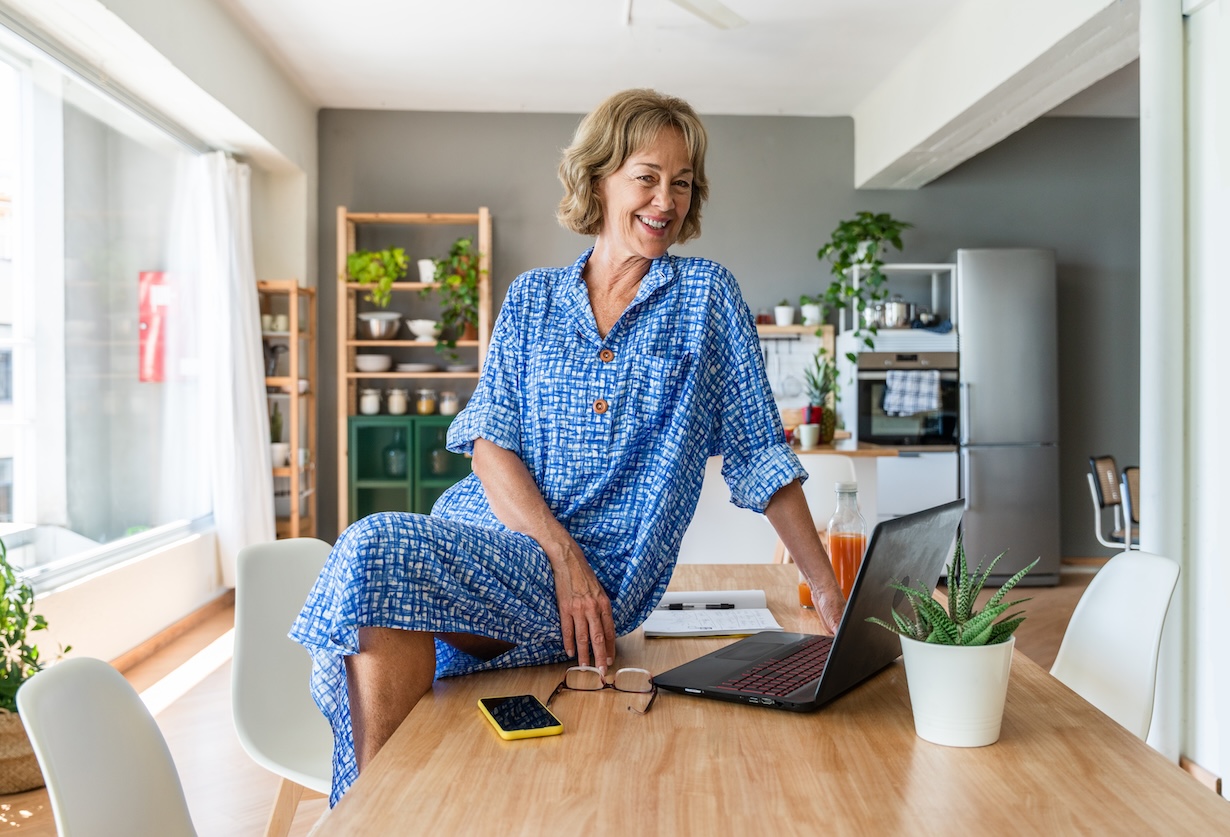 Frau im Pyjama in der Küche vor Computer